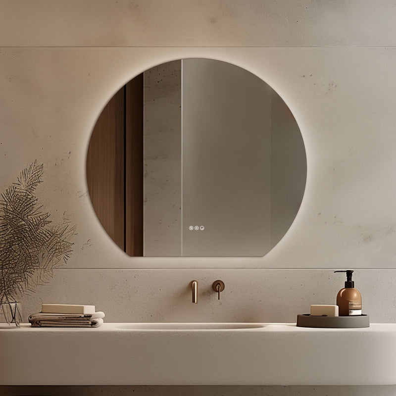 Claris Round Cut 100 x 90cm LED bathroom mirror with touch sensor and backlit frame, styled in a warm neutral bathroom with brushed bronze tap and modern basin - Origins Living mirror at BathLab
