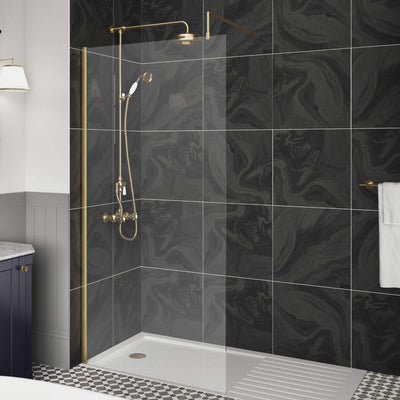 Vista 8mm Brushed Brass Walk In Shower Screen And Support Arm, shown with a gloss white walk in shower tray in a traditional dark grey and black bathroom